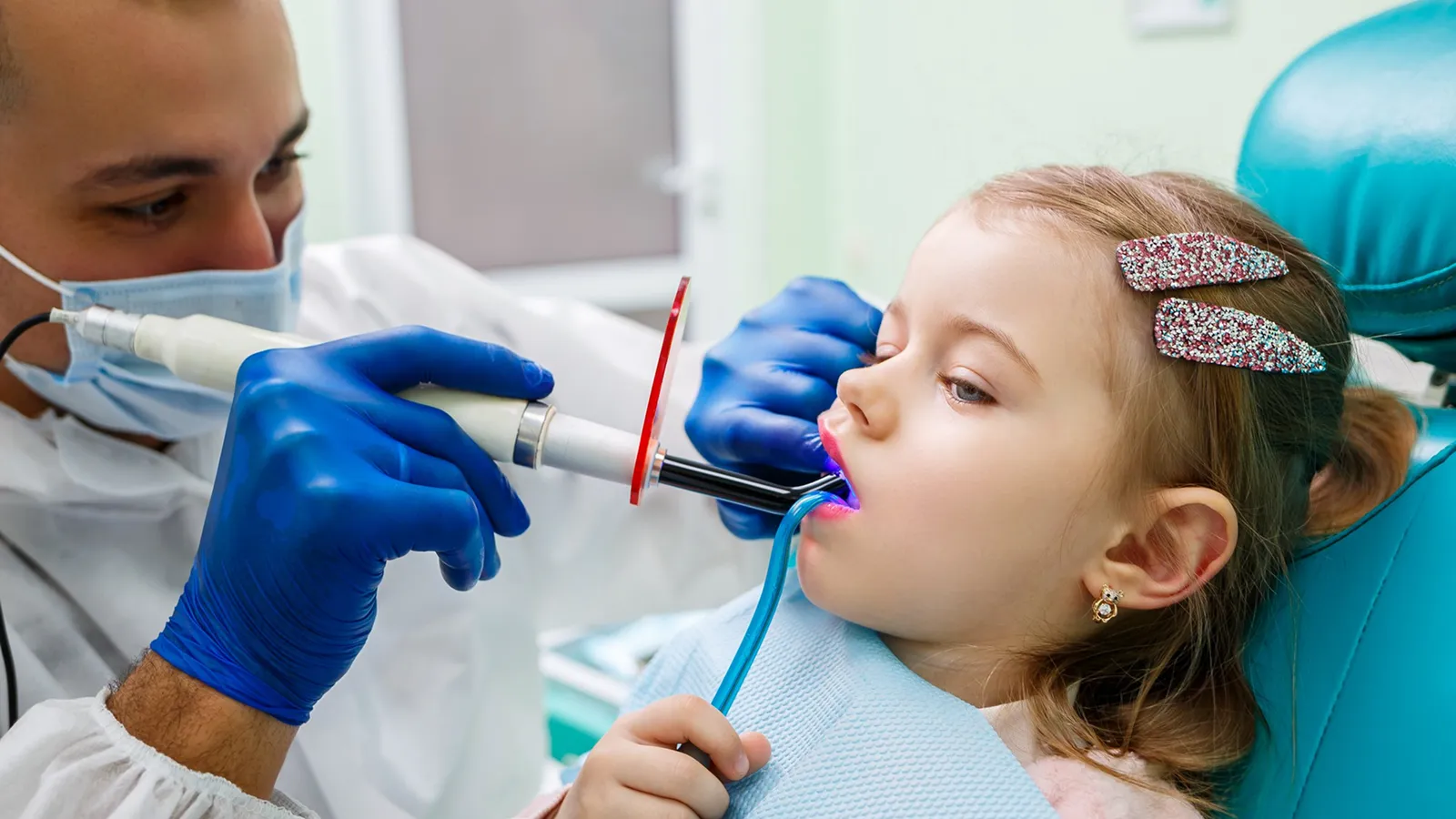 Pediatric dentist applying fluoride treatment to a child's teeth